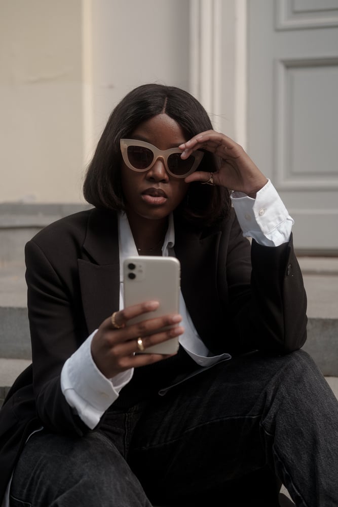 Woman in Black Outfit on Stairs While Using Smartphone